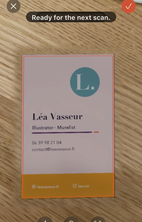 The scanning screen: a pink business card on a wooden table, outlined by the app.