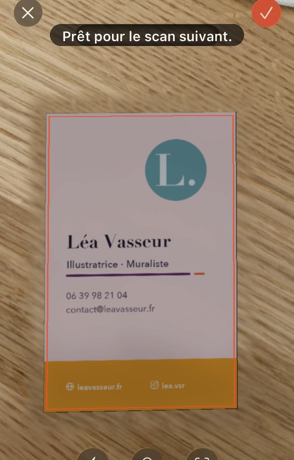 Écran de scan : une carte de visite rose posée sur du bois, détourée par l’application.